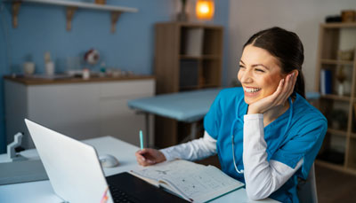 A nurse works at their laptop computer