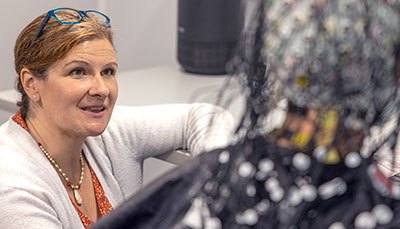 Researcher working with a person wearing a cap on their head with lots of wires coming off of it.