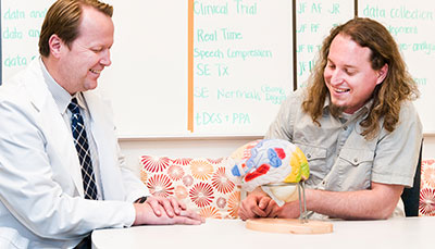 Instructor and student looking at a brain model