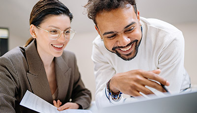 Two people talking with each other and looking at documents.