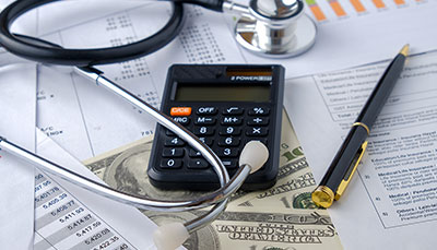 A papers with charts and data with a stethoscope and calculator sitting on top of them.