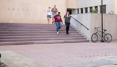 Three students talking, sitting outdoors at Gambrell Hall.