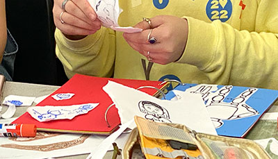 A person's hands tearing paper for an art project. 
