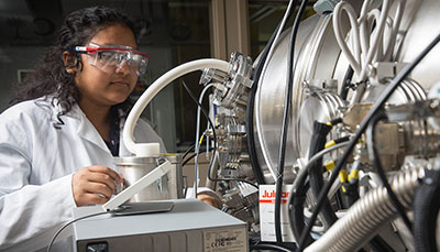 Student wearing safety glasses working at a large piece of equipment. 
