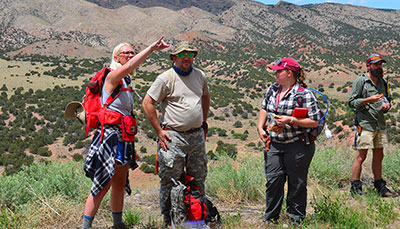 Group of students out in the field surrounded by mountians. 