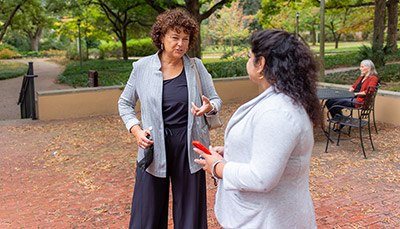 Two people talking with each other in an outside setting.