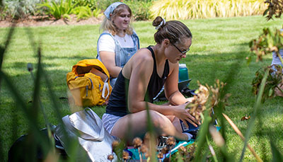 Student sitting on a blanket in an outdoor class. 