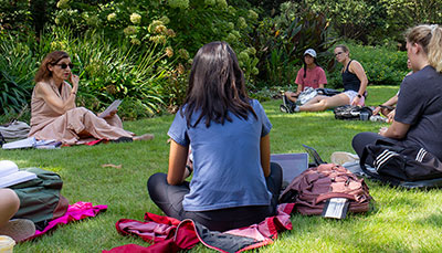 Professor holding a class outside in a lush garden.