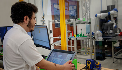 Student in front of computers and using a device.