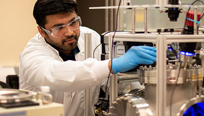 Student in lab gear working on a device.