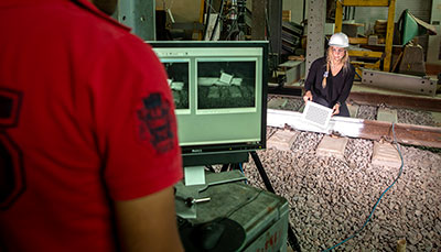 Two students looking at a computer and examining a railroad track.