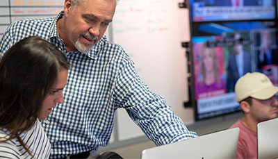Professor talking with a student at a computer. 