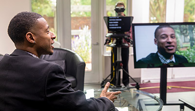 man sitting in front of camera and teleprompter