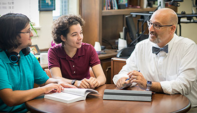 Two students and a professor sat at a table.