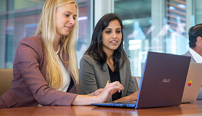 Two business professionals at a table with laptops. 