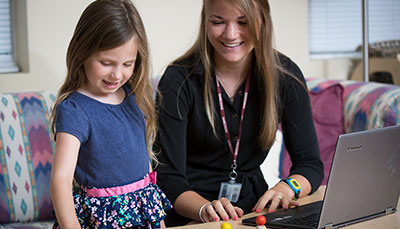 Student teacher observing and playing with a young child.