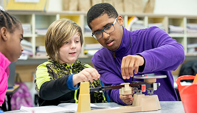 Student teacher working with students in a classroom.
