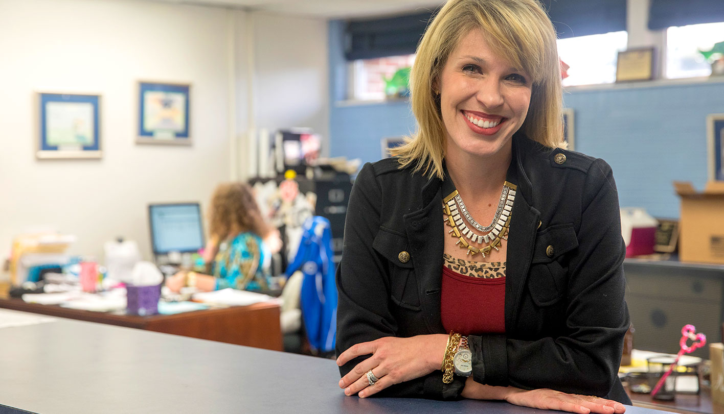 Education administrator standing at the counter in a school office. 