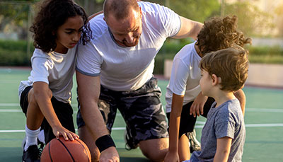 Coach huddled with a group of students on a basketball court.