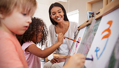 Teacher watching young children painting. 