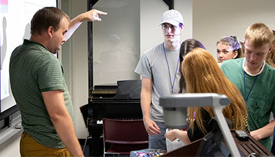 Professor teaching with a class gathered around.