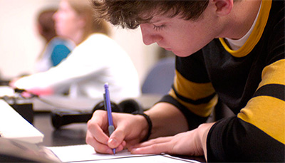 student sitting in front of keyboard writing in notebook