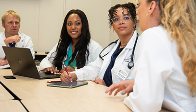 A group of nurses sitting at a table and talking with each other.