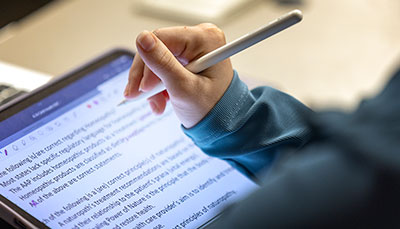 Student taking notes on a tablet. 