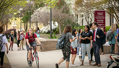 Large collection of students on walkway near campus science building.